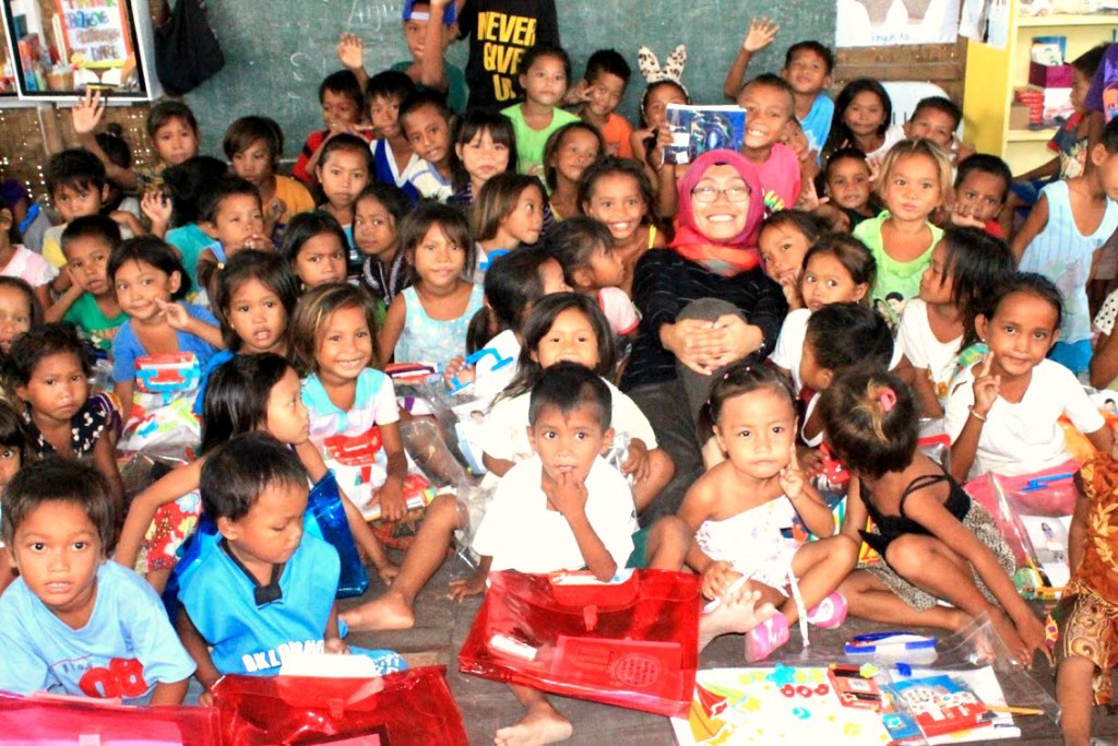 Fatima (center, with glasses), spending downtime with the Bajau young learners after turning over school supplies from donors